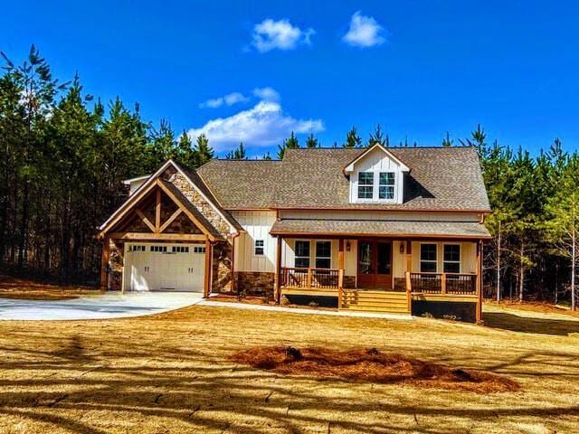 view of front facade with stone siding, a porch, board and batten siding, concrete driveway, and an attached garage