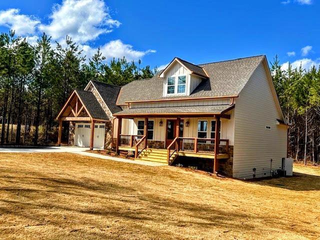 view of front facade with a garage, driveway, a front lawn, covered porch, and crawl space