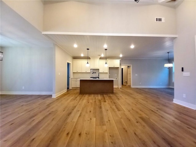 136 Rainey Rd, Temple, GA 30179 - kitchen featuring open floor plan, light wood finished floors, white cabinetry, a center island with sink, and recessed lighting