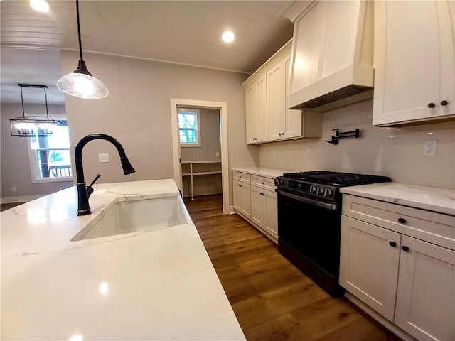 136 Rainey Rd, Temple, GA 30179 - kitchen featuring black range with gas cooktop, premium range hood, wood finished floors, white cabinets, and decorative light fixtures