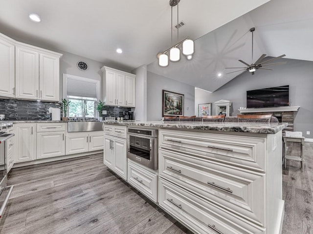 430 Cajun Dr, Ellijay, GA 30540 - kitchen with ceiling fan, light wood finished floors, white cabinetry, tasteful backsplash, and vaulted ceiling