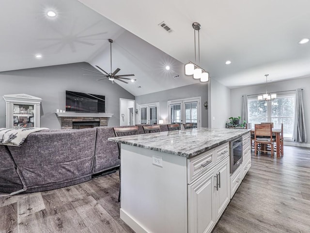 430 Cajun Dr, Ellijay, GA 30540 - kitchen featuring white cabinets, wood finished floors, light stone countertops, a stone fireplace, and recessed lighting