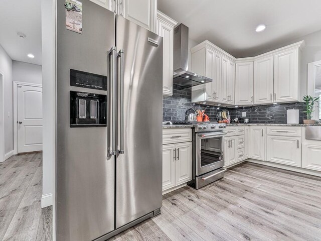 430 Cajun Dr, Ellijay, GA 30540 - kitchen featuring stainless steel appliances, wall chimney range hood, light wood-style flooring, white cabinetry, and decorative backsplash