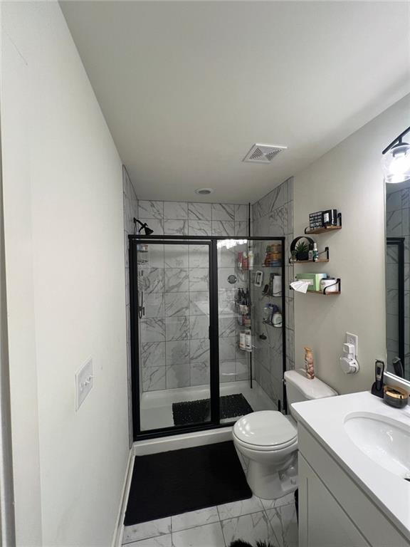 bathroom featuring toilet, an enclosed shower, and vanity