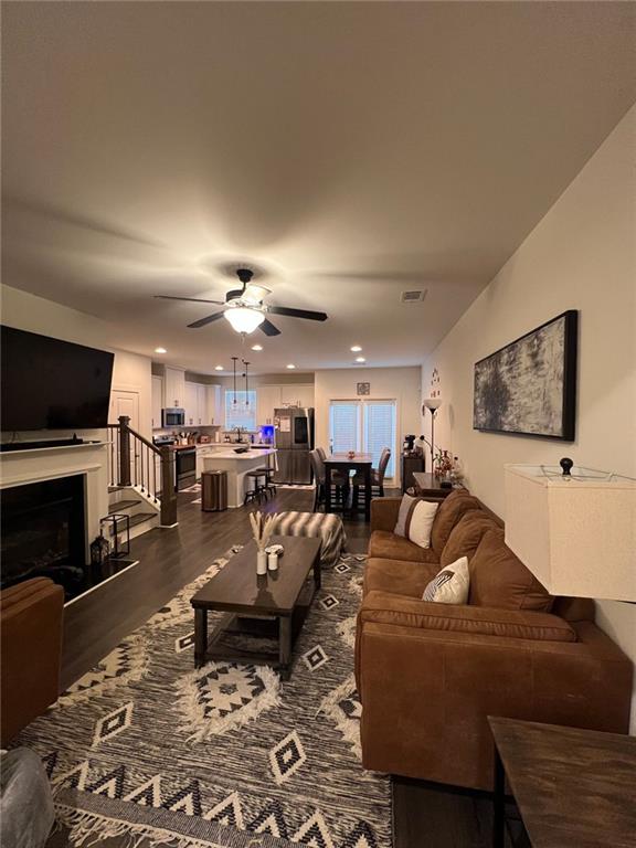 living room featuring ceiling fan and dark hardwood / wood-style floors