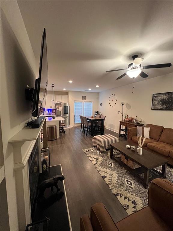 living room featuring ceiling fan and dark hardwood / wood-style floors