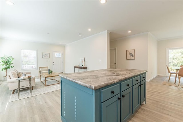 kitchen with light hardwood / wood-style flooring, a healthy amount of sunlight, a kitchen island, and light stone counters