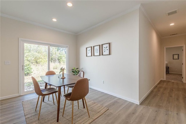 dining area featuring light wood-type flooring and crown molding