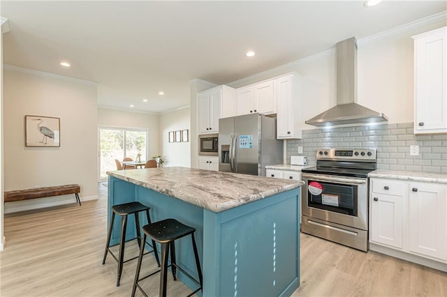 kitchen featuring a kitchen island, wall chimney exhaust hood, light hardwood / wood-style flooring, appliances with stainless steel finishes, and white cabinets