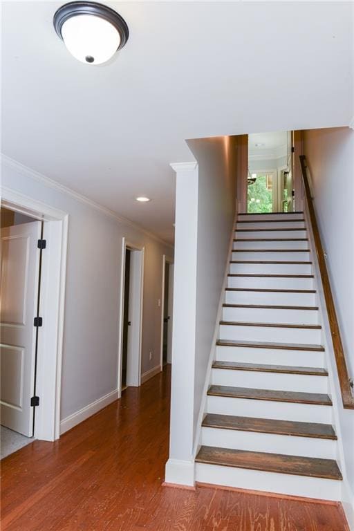 stairway featuring dark wood-type flooring and crown molding