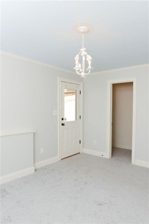 spare room featuring crown molding, a notable chandelier, and light colored carpet