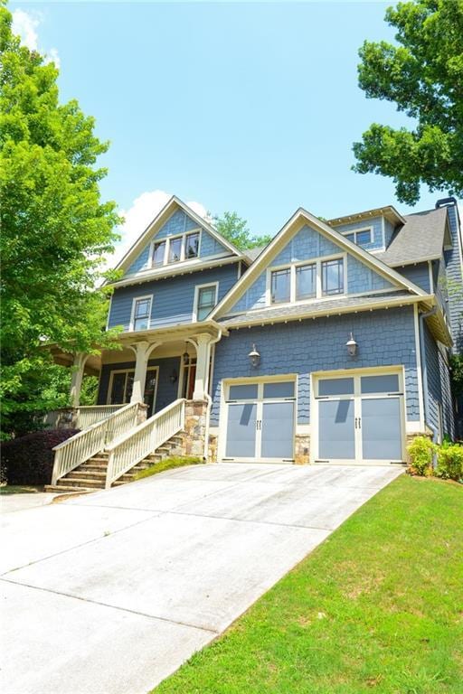 view of front of home featuring covered porch, a front yard, and a garage