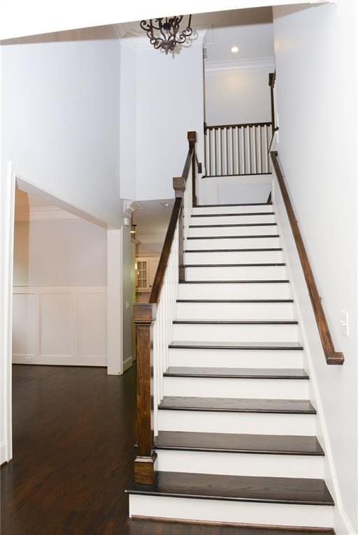 stairs with crown molding, a notable chandelier, and dark hardwood / wood-style floors