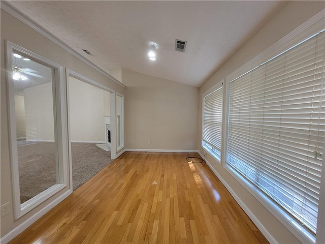 spare room with baseboards, a fireplace with flush hearth, visible vents, and light wood-style floors