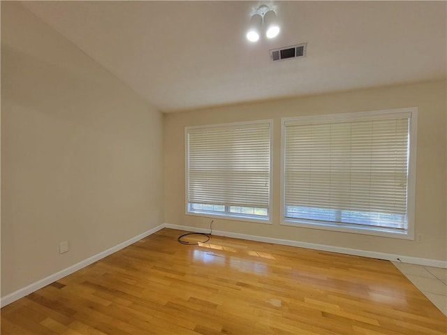 spare room with a wealth of natural light, baseboards, visible vents, and wood finished floors