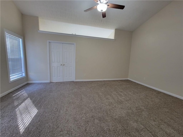 spare room featuring vaulted ceiling, ceiling fan, carpet flooring, and baseboards