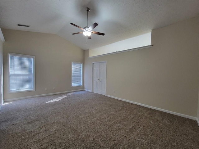 carpeted empty room featuring ceiling fan, baseboards, visible vents, and vaulted ceiling