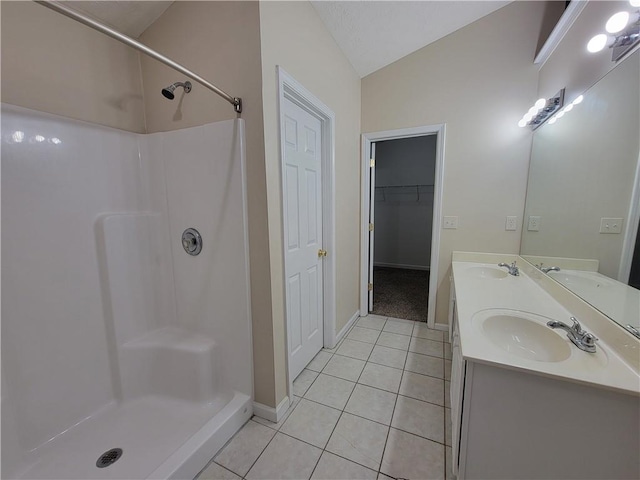 full bathroom with a stall shower, tile patterned flooring, vaulted ceiling, and a sink