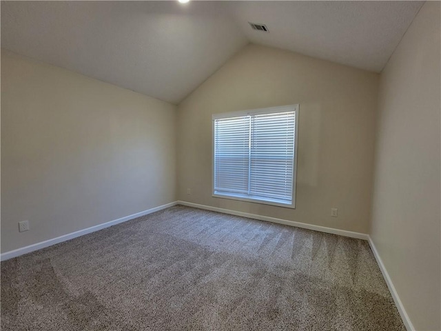 carpeted spare room featuring lofted ceiling, visible vents, and baseboards