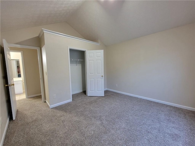 unfurnished bedroom featuring baseboards, carpet, vaulted ceiling, a textured ceiling, and a closet