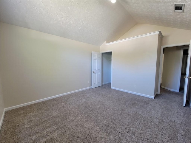 interior space featuring carpet floors, visible vents, vaulted ceiling, a textured ceiling, and baseboards