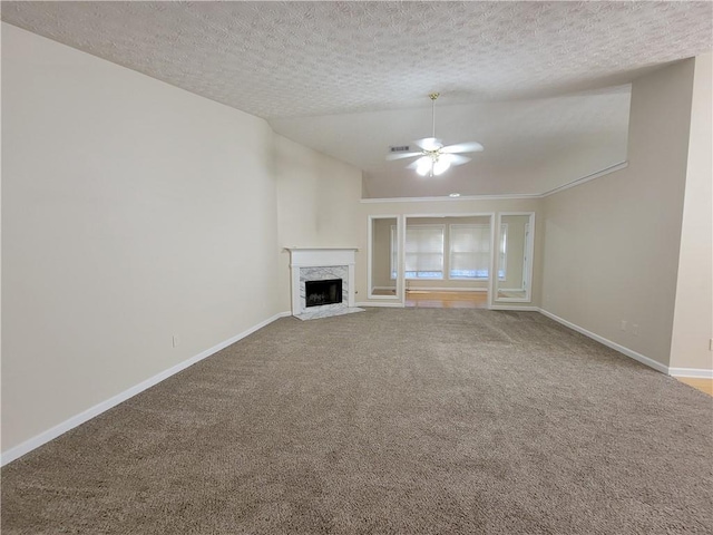 unfurnished living room with a fireplace, lofted ceiling, visible vents, carpet flooring, and baseboards