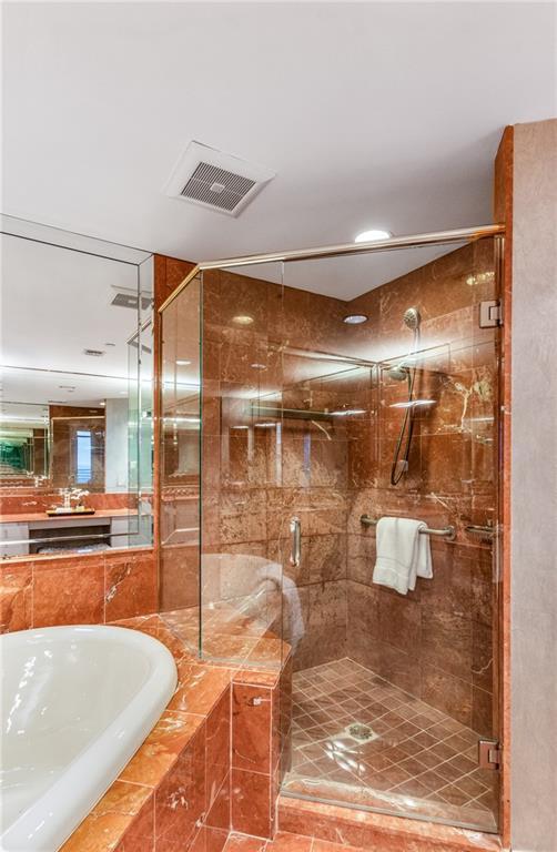 750 Park Ave NE Unit 19E, Atlanta, GA 30326 - bathroom featuring a bath, visible vents, and a shower stall