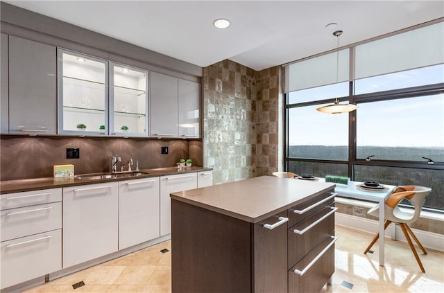 750 Park Ave NE Unit 19E, Atlanta, GA 30326 - kitchen with light tile patterned floors, a sink, white cabinetry, backsplash, and a center island