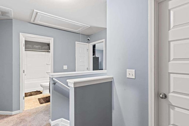 interior space featuring carpet flooring, visible vents, an upstairs landing, baseboards, and attic access