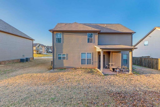 rear view of property with fence, a lawn, and a patio