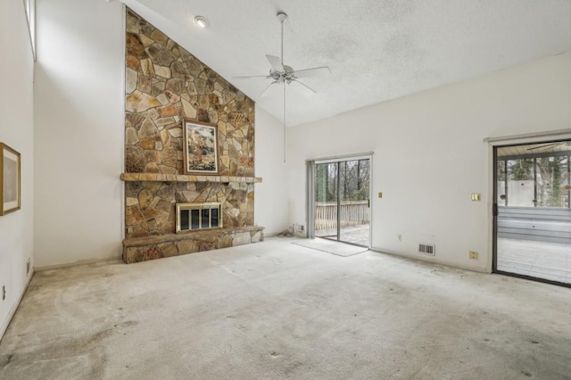 unfurnished living room with a stone fireplace, visible vents, a textured ceiling, and carpet