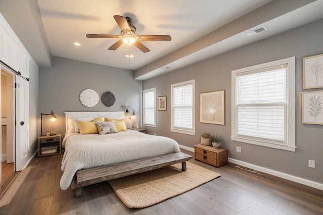 bedroom with a barn door, recessed lighting, baseboards, wood finished floors, and visible vents
