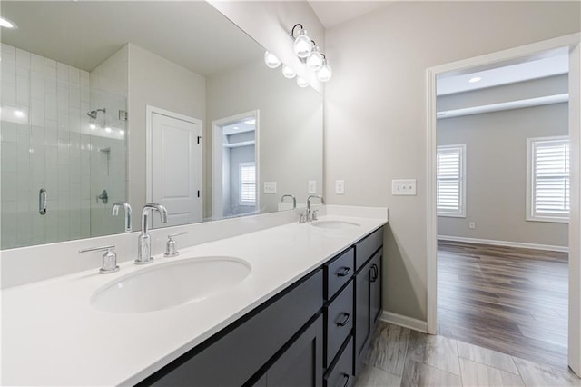 full bathroom with a sink, baseboards, a shower stall, and double vanity