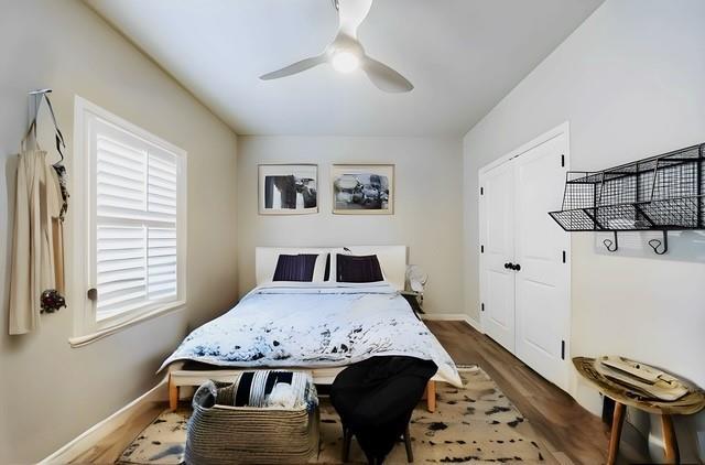 bedroom featuring a ceiling fan, baseboards, wood finished floors, and a closet