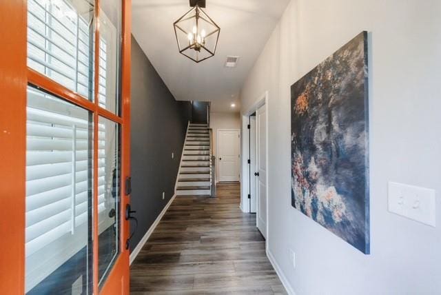 hall with baseboards, wood finished floors, a chandelier, and stairway