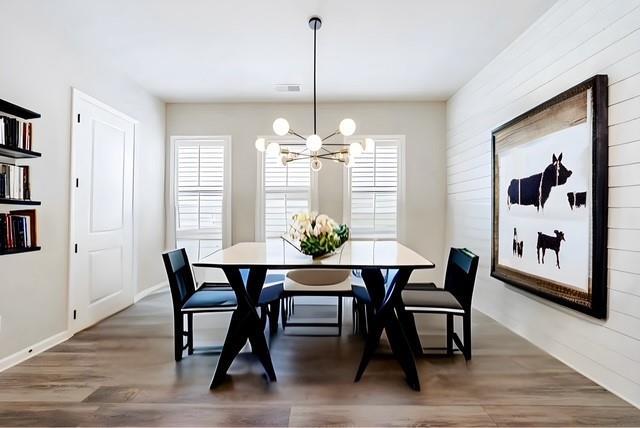 dining space featuring a notable chandelier, wood finished floors, and visible vents