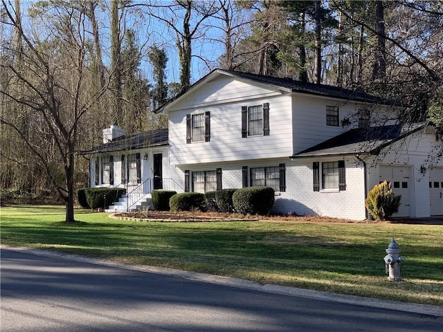 split level home with a chimney, brick siding, and a front lawn