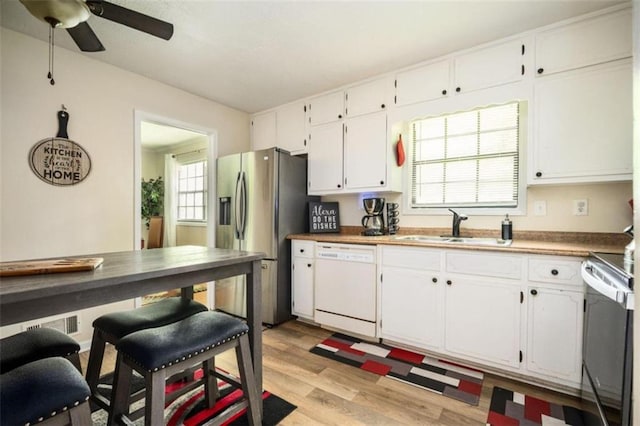 kitchen with stainless steel fridge, white dishwasher, a sink, and white cabinets