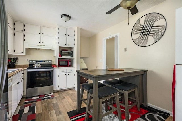 kitchen featuring electric stove, white cabinetry, wood finished floors, built in microwave, and under cabinet range hood