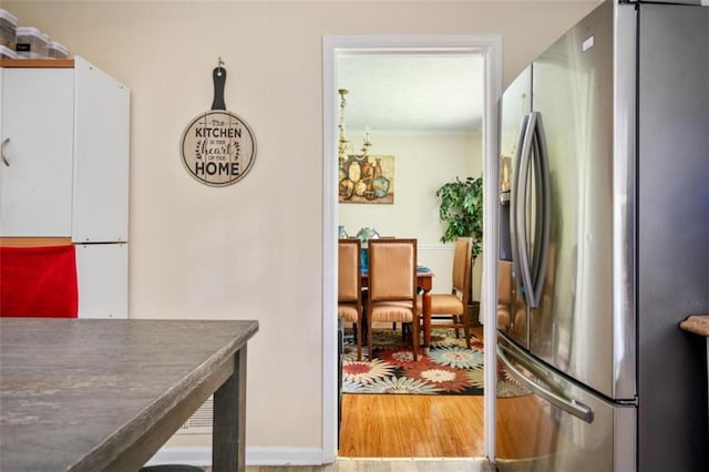 kitchen with dark countertops, white cabinets, stainless steel refrigerator with ice dispenser, and wood finished floors