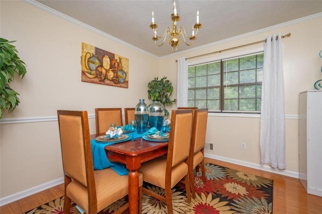 dining area with wood finished floors, crown molding, baseboards, and an inviting chandelier