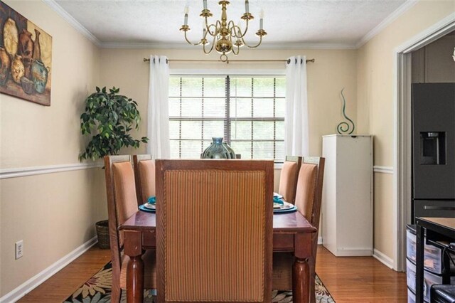 dining space with baseboards, ornamental molding, wood finished floors, and a notable chandelier