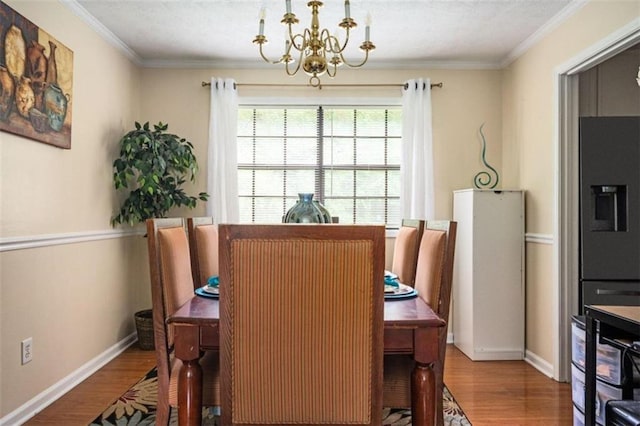 dining room featuring an inviting chandelier, wood finished floors, baseboards, and crown molding
