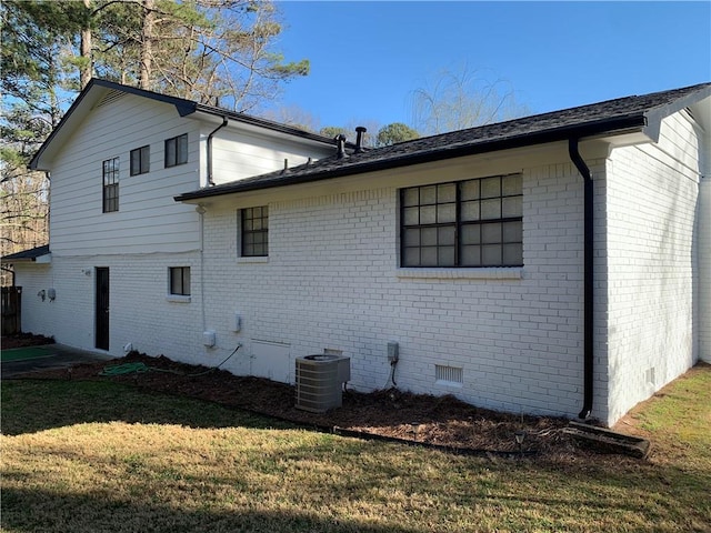 view of side of home with central AC unit, a yard, brick siding, and crawl space