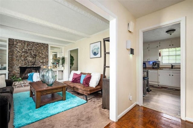 living area with a fireplace, baseboards, and beam ceiling