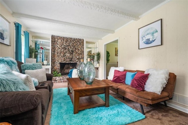 living room with ornamental molding, a stone fireplace, beamed ceiling, and carpet