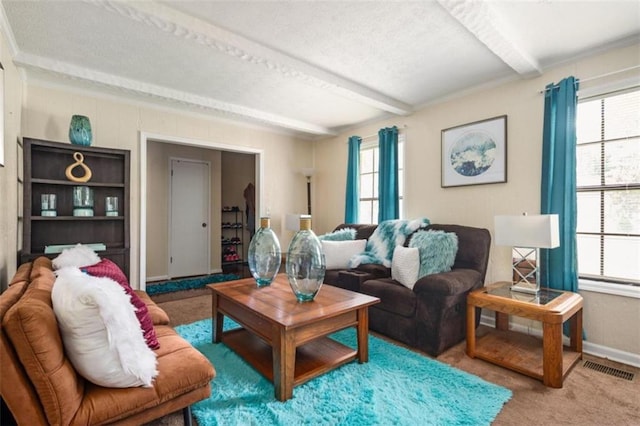 carpeted living area with beamed ceiling, visible vents, and baseboards