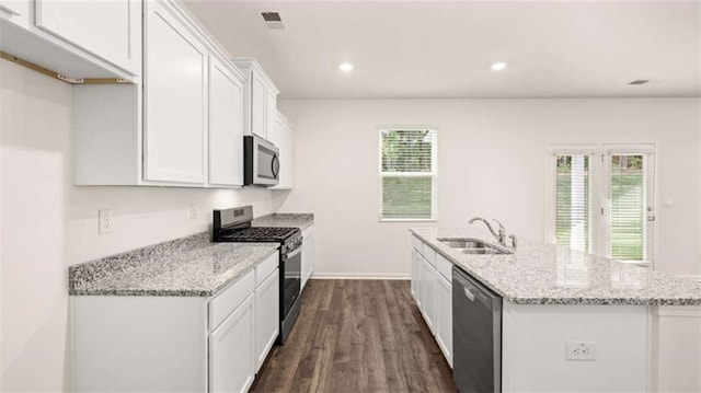 kitchen with light stone countertops, appliances with stainless steel finishes, dark wood-type flooring, sink, and white cabinets