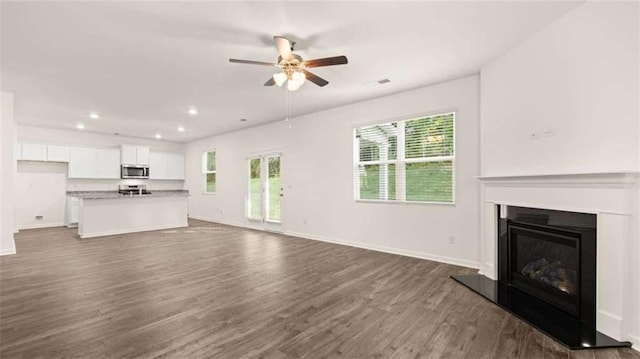 unfurnished living room featuring ceiling fan and dark hardwood / wood-style floors