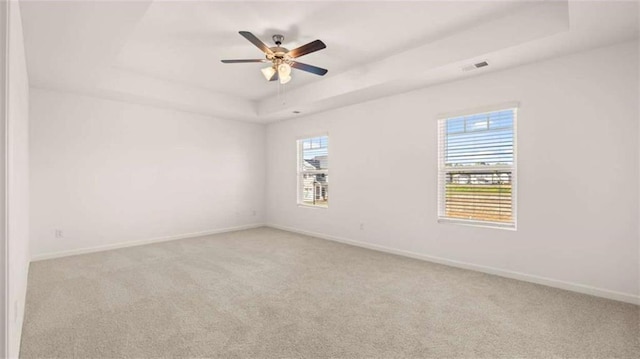 unfurnished room with a tray ceiling, ceiling fan, and light colored carpet